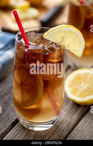 Cocktail con tè freddo lungo dell'isola con fette di limone all'aperto su un tavolo rustico in legno Foto Stock