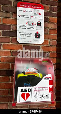 Defibrillatore automatico esterno installato all'esterno di un bagno in un parco pubblico. I defibrillatori semiautomatici esterni sono collegati in modalità wireless direttamente al sistema di gestione delle chiamate 911 Foto Stock