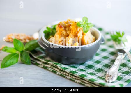 Porridge di piselli cotto con spezie e condimenti in un recipiente di ceramica su un tavolo di legno. Foto Stock