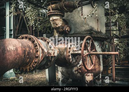 Tubi e tubi fortemente arrugginiti con vernice di pelatura di una vecchia fabbrica abbandonata Foto Stock