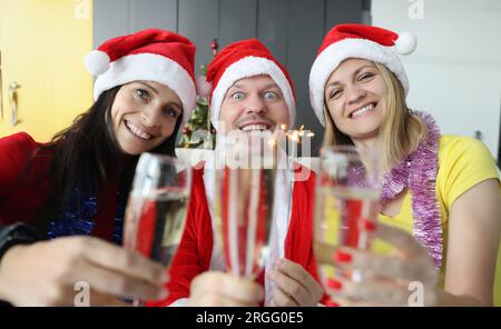 Uomo e donna in babbo natale cappelli bere champagne e tenere scintille nelle loro mani Foto Stock