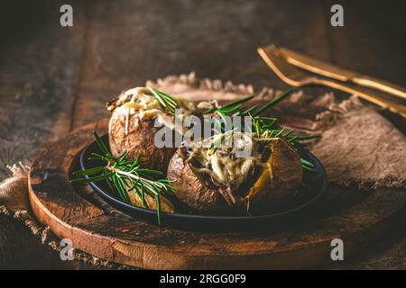 Patate al forno con funghi, panna acida e formaggio su sfondo rustico in legno, spazio per copiare Foto Stock