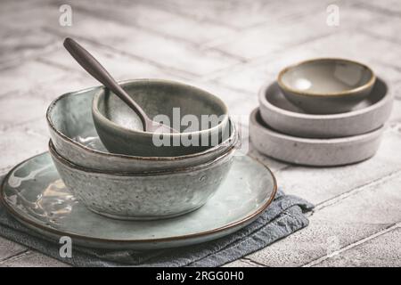 Piatti e ciotole in gres grigio su un tavolo rustico, spazio copia Foto Stock