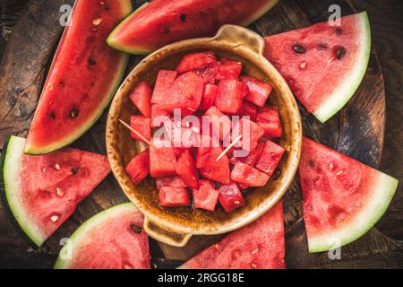 Anguria fresca tagliata a fette su sfondo rustico in legno, vista dall'alto Foto Stock
