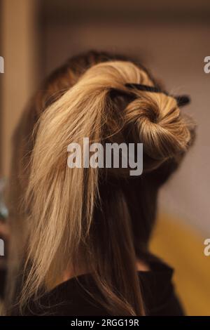 Preparazione dell'acconciatura femminile su capelli lunghi biondi. Vista posteriore. Preparazione dietro le quinte Foto Stock