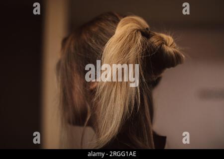 Preparazione dell'acconciatura femminile su capelli lunghi biondi. Vista laterale. Preparazione dietro le quinte Foto Stock