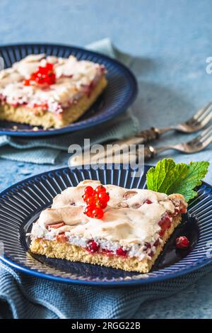 Pezzo di torta di ribes fatta in casa con meringa croccante su un piatto blu su sfondo blu Foto Stock