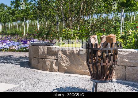 Cesto di metallo pieno di legno in un giardino Foto Stock