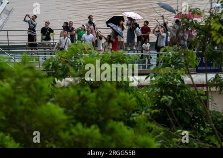 (230809) -- NINGMING, 9 agosto 2023 (Xinhua) -- i turisti guardano le pitture rupestri di Huashan nella contea di Ningming, nella città di Chongzuo, nella regione autonoma di Guangxi Zhuang nel sud della Cina, 8 agosto 2023. Il sito di Zuojiang Huashan ospita oltre 1.900 disegni ben conservati sulla faccia delle montagne Huashan lungo il fiume Zuojiang e il suo affluente Mingjiang a Chongzuo. I dipinti di rosso brunastro, creati dal periodo degli Stati combattenti (475-221 a.C.) alla dinastia Han orientale (25-220), raffigurano i sacrifici del popolo Luoyue, antenati dell'odierna minoranza etnica Zhuang. Si dice che il maggiore Foto Stock