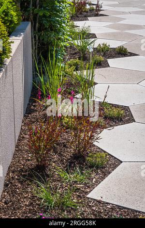 Sentiero con grandi lastre di pietra attraverso un giardino splendidamente piantato, verticale Foto Stock