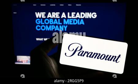 Persona che possiede uno smartphone con il logo della società di intrattenimento statunitense Paramount Global sullo schermo davanti al sito Web. Concentrarsi sul display del telefono. Foto Stock