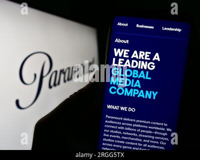 Persona che possiede uno smartphone con il sito Web della società di intrattenimento statunitense Paramount Global sullo schermo davanti al logo. Concentrarsi sul centro del display del telefono. Foto Stock