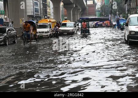 Dhaka, Bangladesh. 9 agosto 2023. I veicoli provano a guidare e i cittadini camminano per le strade di disboscamento d'acqua a Dacca, Bangladesh, il 9 agosto 2023. Il pesante deflusso dei monsoni ha causato un eccessivo disboscamento delle acque nella maggior parte delle aree della città di Dacca, Bangladesh. Le strade erano sommerse rendendo il viaggio lento e pericoloso. Credito: Mamunur Rashid/Alamy Live News Foto Stock