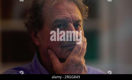 Un uomo anziano penoso ha perso nel pensiero. Una persona maschile più anziana contemplativa vista attraverso la riflessione della finestra la sera Foto Stock