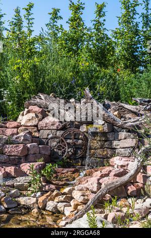 Giardino naturale con pietre, legno antico e corso d'acqua Foto Stock