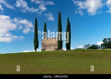 Ponsacco, PI, Italia-7 giugno 2023; vista dall'angolo basso della chiesetta di San Pierino circondata da cipressi mediterranei tipici di la italiana Foto Stock