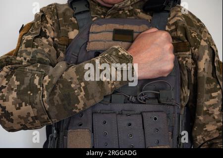 Soldato ucraino in forma di pixel militare e giubbotto antiproiettile con bandiera Ucraina e braccio vicino a hart. Foto Stock