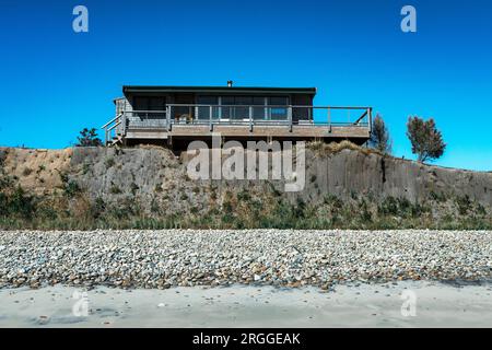 Casa sulla spiaggia minacciata dall'erosione costiera, Stonewall Beach Foto Stock