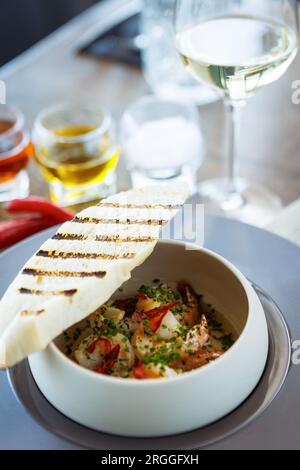 Gamberi PIL-PIL. Gamberoni, aglio, peperoncino e baguette. Delizioso primo piano del cibo tradizionale spagnolo servito per pranzo in una moderna cucina gourmet Foto Stock