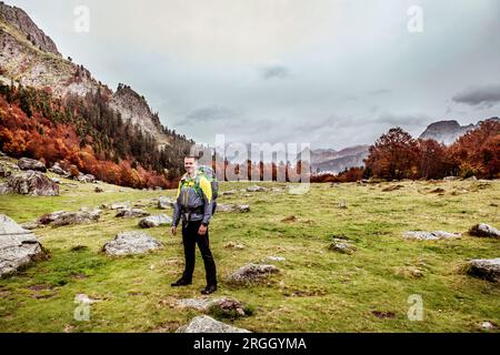 Ritratto di uomo sorridente escursionismo nel campo al di sotto della montagna Foto Stock