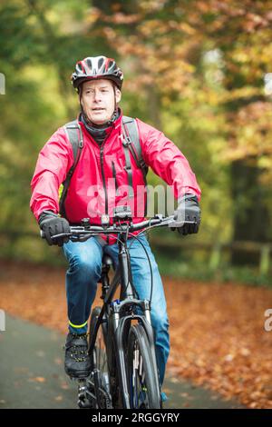 Uomo maturo in giacca rossa il pendolarismo in bicicletta Foto Stock