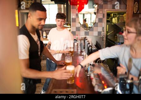 Barista che serve birra a un cliente in un bar Foto Stock