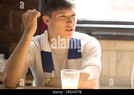 Giovane seduto con una pinta di birra. Foto Stock