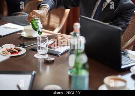 Imprenditore versando acqua dalla bottiglia Foto Stock