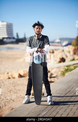 Giovane uomo appoggiato su skateboard Foto Stock