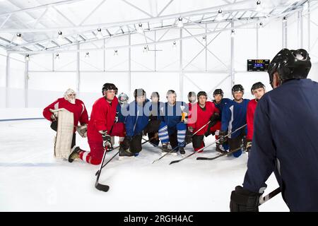 Gruppo di giocatori di hockey su ghiaccio che si inginocchiano sulla pista di pattinaggio Foto Stock