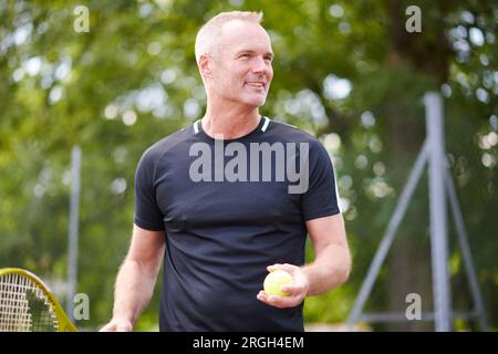 Uomo maturo con racchetta da tennis e palla Foto Stock