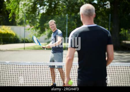 Uomini maturi che giocano a tennis Foto Stock
