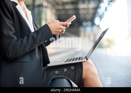 Donna d'affari che usa smartphone e laptop sulla piattaforma del treno Foto Stock