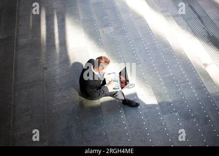Vista dall'alto dell'uomo d'affari che utilizza un computer portatile sulla scala Foto Stock
