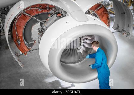 Uomo che lavora al motore dell'aereo nell'hangar Foto Stock