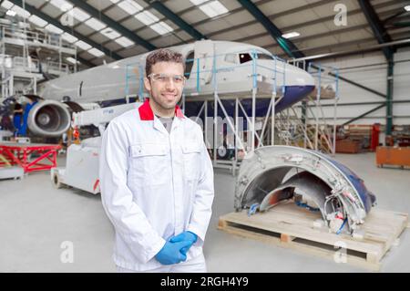 Ritratto di un giovane lavoratore maschio nell'hangar degli aerei Foto Stock