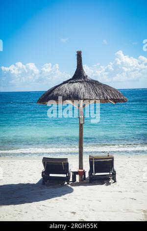 Sedie a sdraio sotto l'ombrellone sulla spiaggia Foto Stock