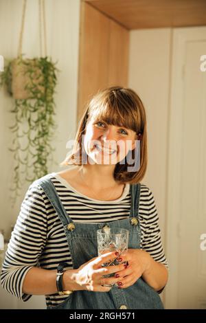 Giovane donna sorridente che regge un bicchiere d'acqua Foto Stock
