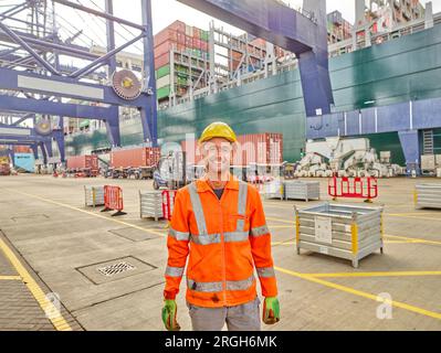Dock sorridente lavoratore in abbigliamento riflettivo e elmetto Foto Stock