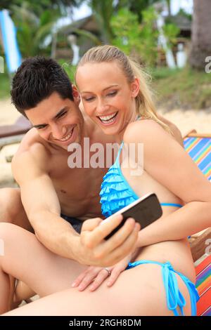 Coppia giovane tenendo selfie sulla spiaggia Foto Stock