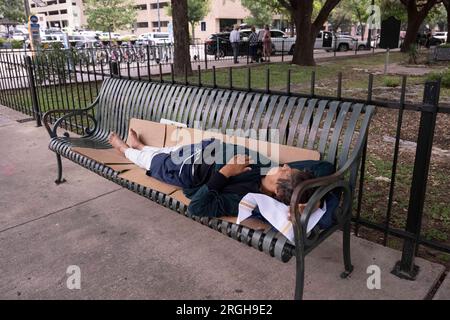 Un uomo riposa su una panchina del parco pubblico di fronte al Campidoglio del Texas all'11° e al Congresso nel centro di Austin l'8 giugno 2023. Foto Stock