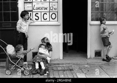 Vita familiare 1970s Regno Unito. Bambini fratelli e sorelle si prendono cura del bambino e del bambino. Stanno aspettando fuori da un disco pub all'ora di pranzo per far riemergere i loro genitori. The Rising Sun, poi cambiato in Paper Moon, 24, Blackfriars Rd, SE1 London 1975 England. HOMER SYKES Foto Stock