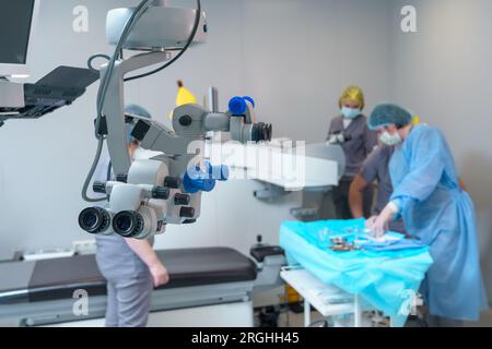 Microscopio chirurgico in sala operatoria con medici. Clinica oftalmologica Foto Stock