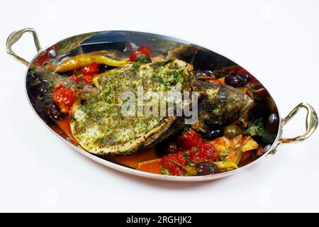 pesce spigola mediterraneo alla griglia con pomodoro, cappero, carciofo e salsa di olive Foto Stock
