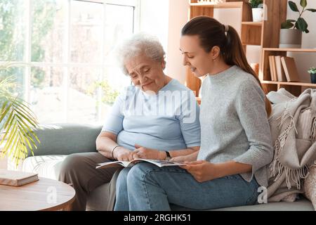 Donna anziana con sua nipote che legge la rivista a casa Foto Stock
