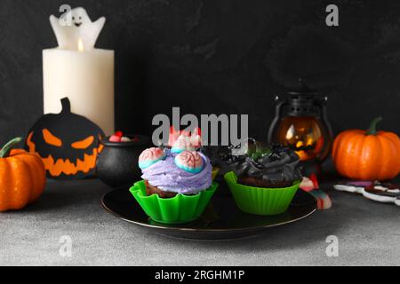 Piatto con deliziosi cupcake e caramelle di Halloween su sfondo scuro, primo piano Foto Stock