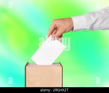 Uomo che mette il suo voto nelle urne su sfondo a colori, primo piano Foto Stock