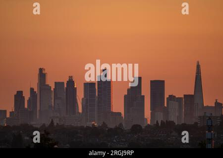 Wimbledon, Londra, Regno Unito. 10 agosto 2023. Temperature a Londra dovute al picco a 25 gradi piacevoli oggi. Un cielo arancione all'alba con i grattacieli del centro di Londra che catturano i primi raggi di luce solare. Crediti: Malcolm Park/Alamy Live News Foto Stock