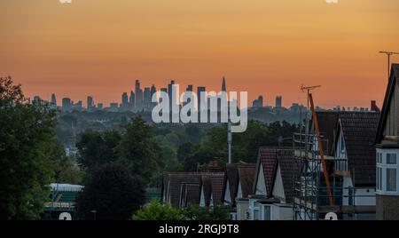 Wimbledon, Londra, Regno Unito. 10 agosto 2023. Temperature a Londra dovute al picco a 25 gradi piacevoli oggi. Un cielo arancione all'alba con i grattacieli del centro di Londra che catturano i primi raggi di luce solare. Crediti: Malcolm Park/Alamy Live News Foto Stock