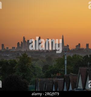 Wimbledon, Londra, Regno Unito. 10 agosto 2023. Temperature a Londra dovute al picco a 25 gradi piacevoli oggi. Un cielo arancione all'alba con i grattacieli del centro di Londra che catturano i primi raggi di luce solare. Crediti: Malcolm Park/Alamy Live News Foto Stock